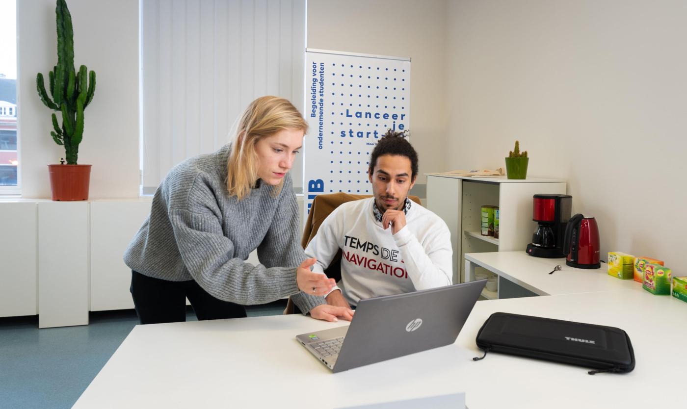 2022_Student Ondernemers Student en studente kijken naar een scherm aan een bureau